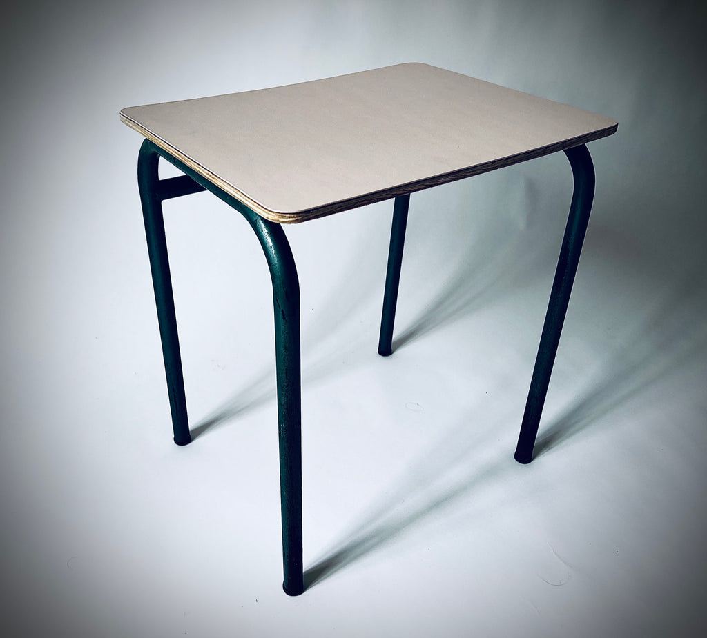 Schrägansicht des Beistelltischs mit hellrosa Forbo-Linoleum, sichtbarer Holzkante und gebogenen dunkelgrünen Metallbeinen.
