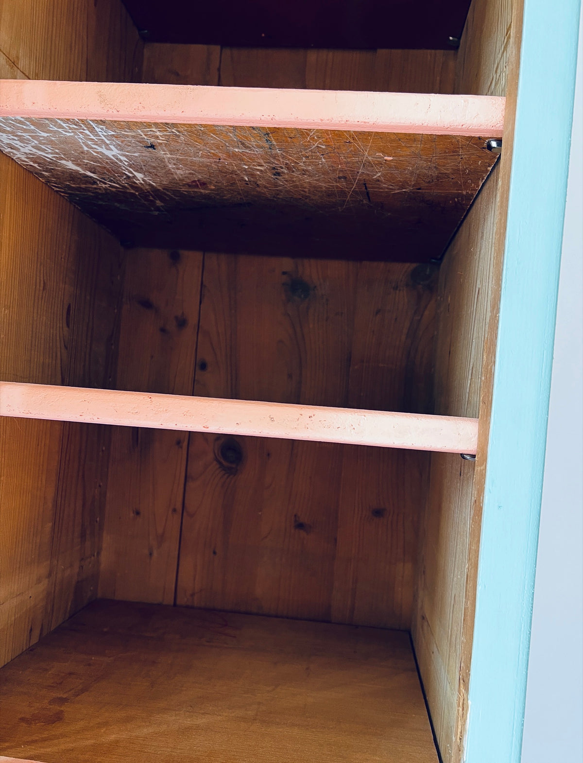 Detail der wiederverwendeten Holztablare mit Farb- und Arbeitsspuren sowie lachsfarbenen Vorderkanten.
