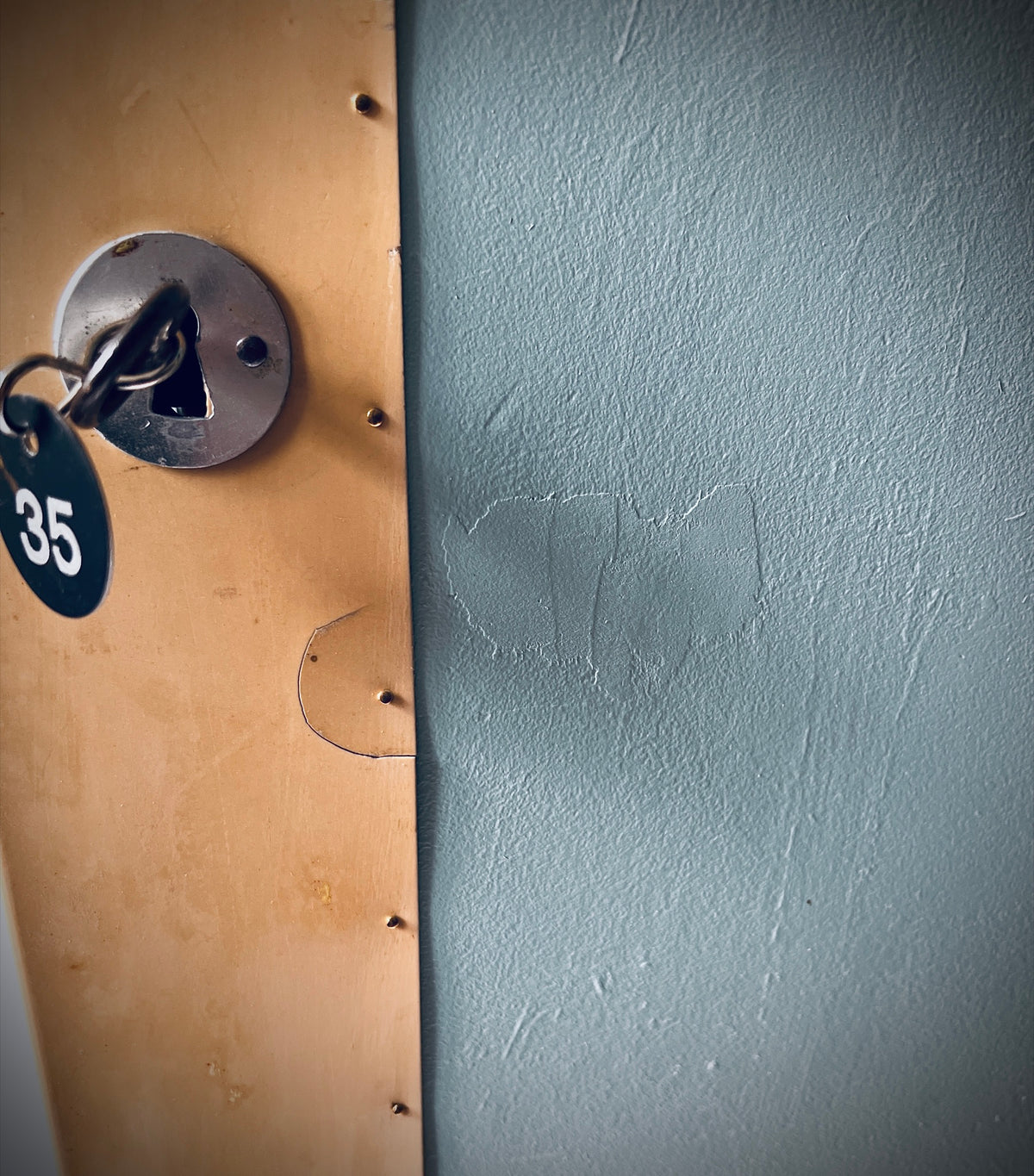 Nahaufnahme von Schlüsselplakette 35, Schlüsselschild, beschädigter Schutzplatte und Narben in der lackierten Türfläche.