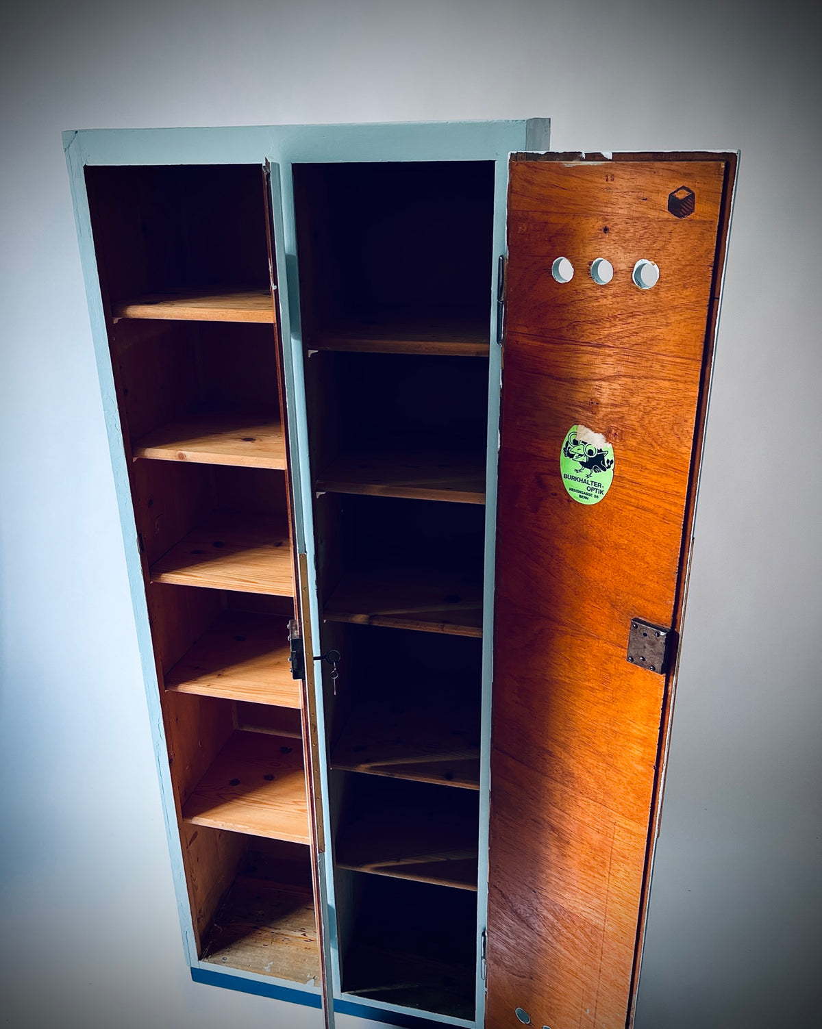 Geöffneter Schrank 35/38 mit zwei getrennten Fächern, Holztablaren und dem Aufkleber an der rechten Türinnenseite.